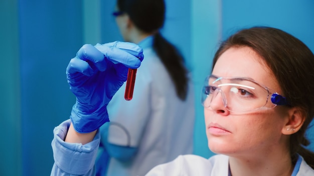 Foto grátis mulher cientista examinando amostras de sangue e líquido trabalhando em um laboratório moderno e equipado