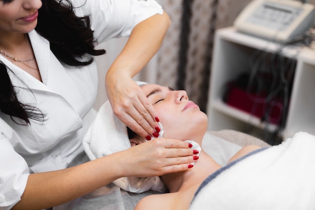 Mulher cliente no salão recebendo massagem facial manual da esteticista