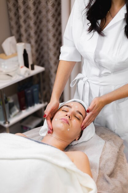 Mulher cliente no salão recebendo massagem facial manual da esteticista