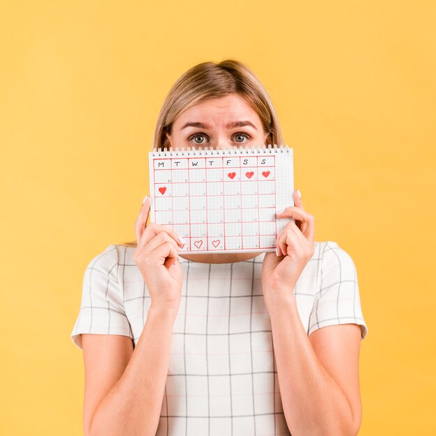 Mulher cobre o rosto com o calendário do período