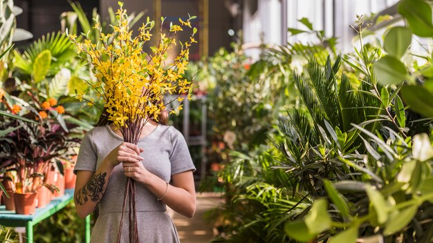 Mulher cobrindo o rosto com buquê de flores amarelas