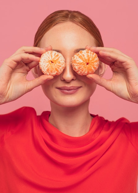 Mulher cobrindo os olhos com laranjas