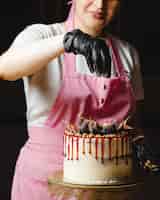 Foto grátis mulher colocando nozes em cima do bolo clássico decorado com figos e calda