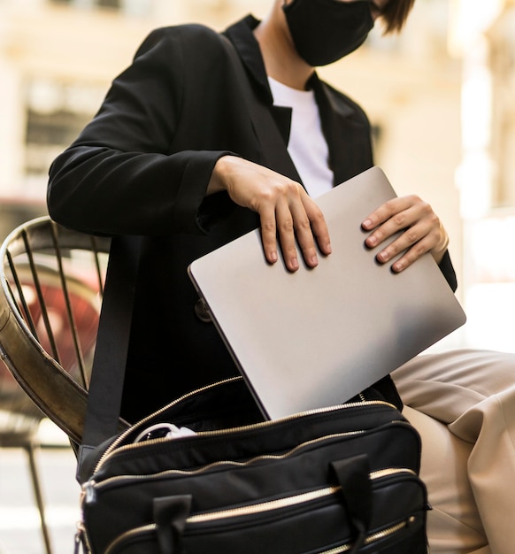 Foto grátis mulher colocando o laptop dentro da bolsa