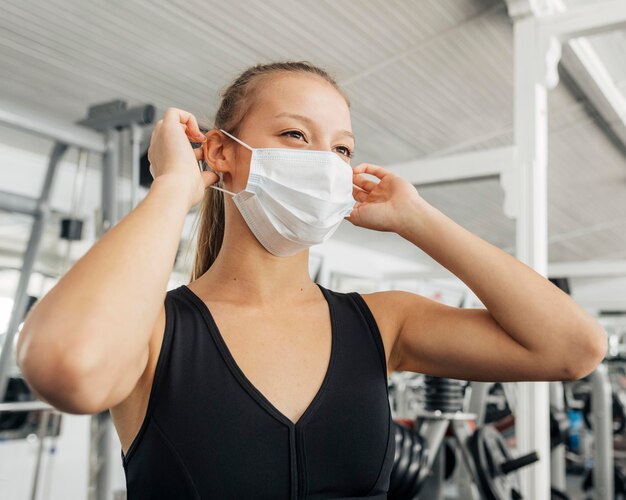 Mulher colocando sua máscara médica na academia