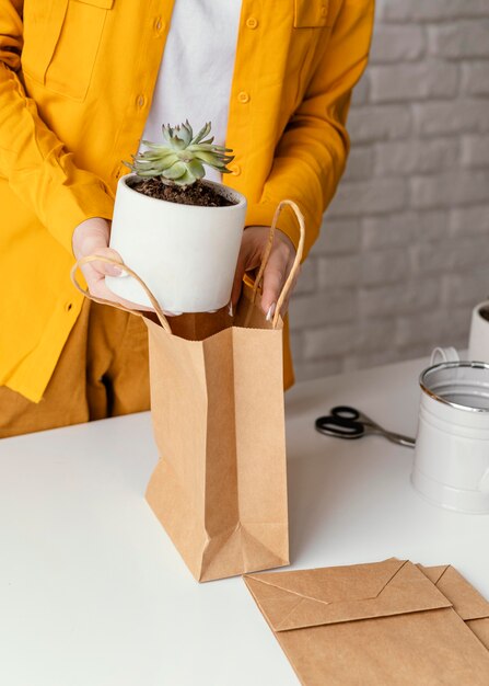 Mulher colocando uma planta em um saco de papel