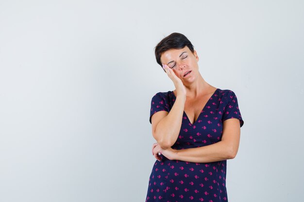 Mulher com a bochecha apoiada na palma da mão no vestido e parecendo com sono