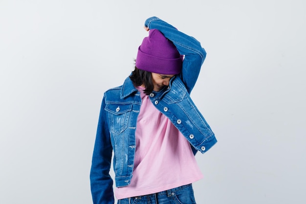 Foto grátis mulher com a cabeça apoiada no braço usando um gorro de jaqueta jeans de ganga parecendo ofendida