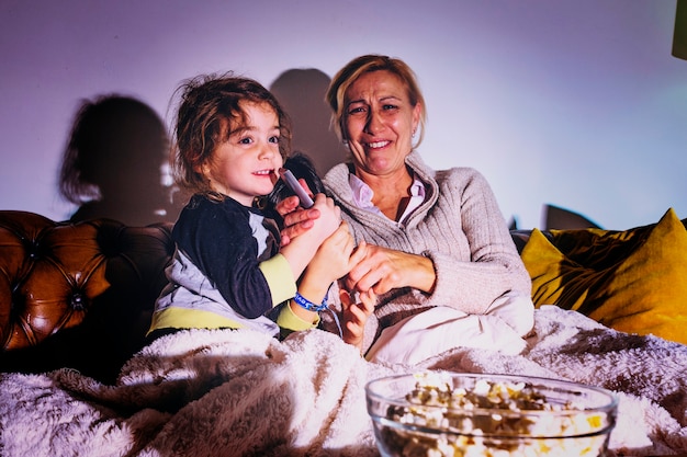 Mulher com as filhas assistindo TV no escuro