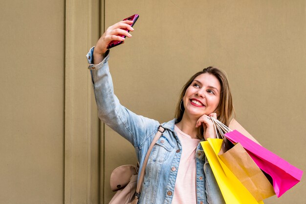 Foto grátis mulher, com, bolsas para compras, levando, selfie, em, parede