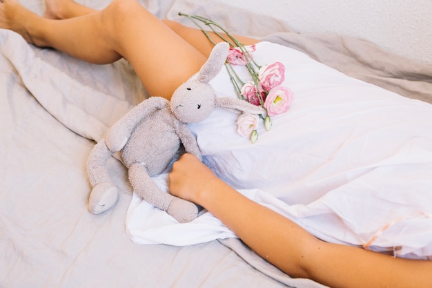 Foto grátis mulher com brinquedo e buquê na cama