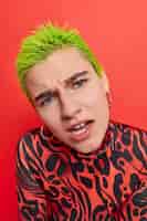 Foto grátis mulher com cabelo verde curto reage a algo desagradável ouve palavras ofensivas usa um macacão casual vermelho