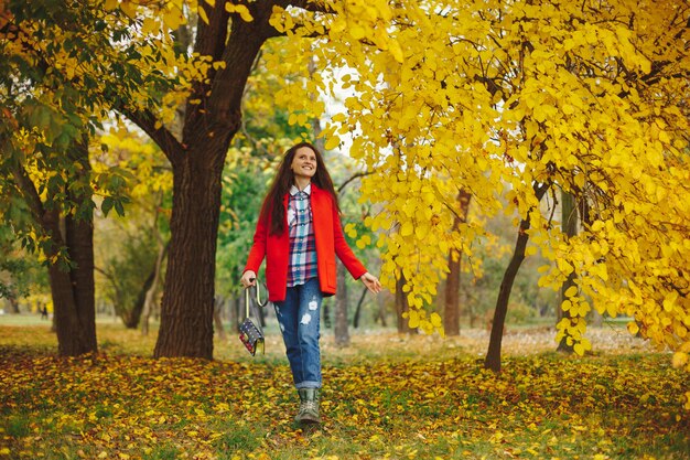 mulher com cabelos longos ondulados, aproveitando o outono no parque.