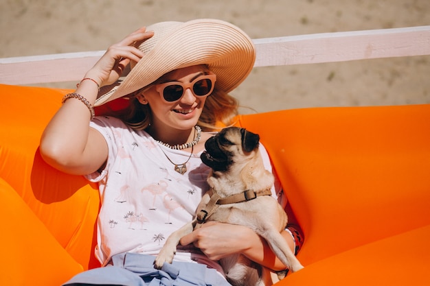 Mulher com cachorro na praia em um colchão de piscina