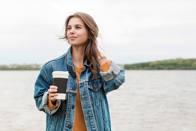 Mulher com café na beira-mar