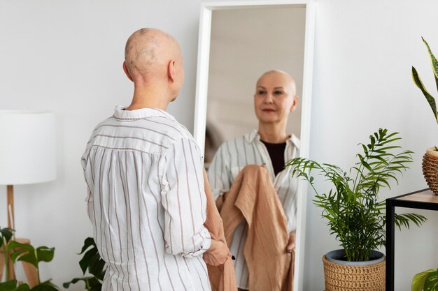 Mulher com câncer de pele se olhando no espelho