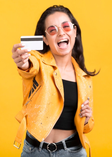 Mulher com casaco amarelo mostrando seu cartão de compras