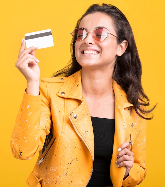 Foto grátis mulher com casaco amarelo mostrando seu cartão tiro médio