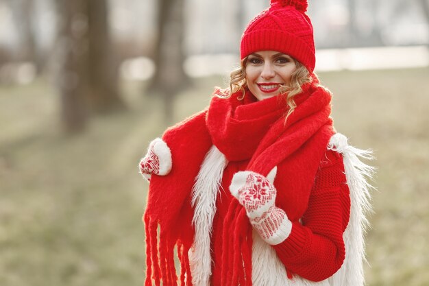 Mulher com chapéu de malha de inverno e lenço olhando para a câmera com um sorriso