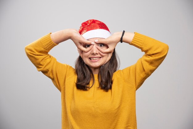 Mulher com chapéu de Papai Noel, mostrando seus alunos.