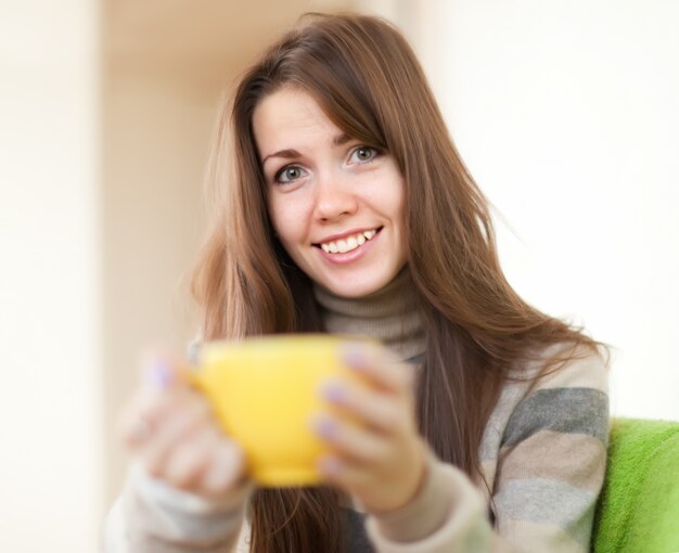 mulher com copo amarelo em casa