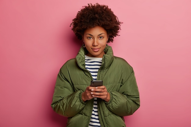 Mulher com corte de cabelo afro, usa suéter listrado e jaqueta de inverno