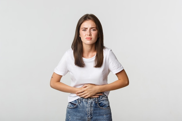 Mulher com dor de estômago, com as mãos na barriga, desconforto de cólicas menstruais. menina com náuseas.