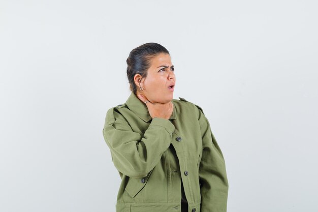 Mulher com dor de garganta na jaqueta, camiseta e parecendo doente.