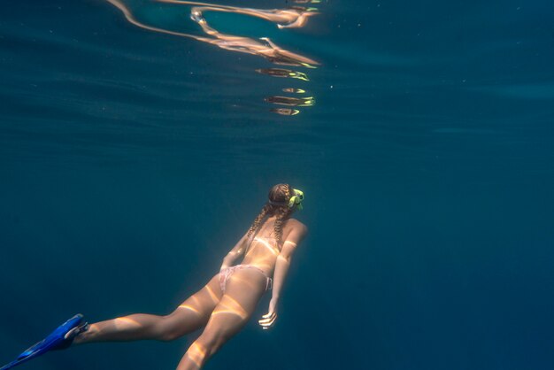 Mulher com equipamento de mergulho nadando no oceano