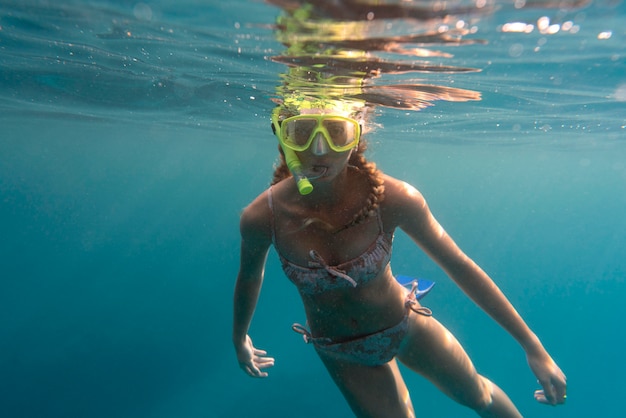 Mulher com equipamento de mergulho nadando no oceano