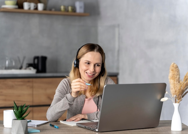 Mulher com fone de ouvido trabalhando no laptop