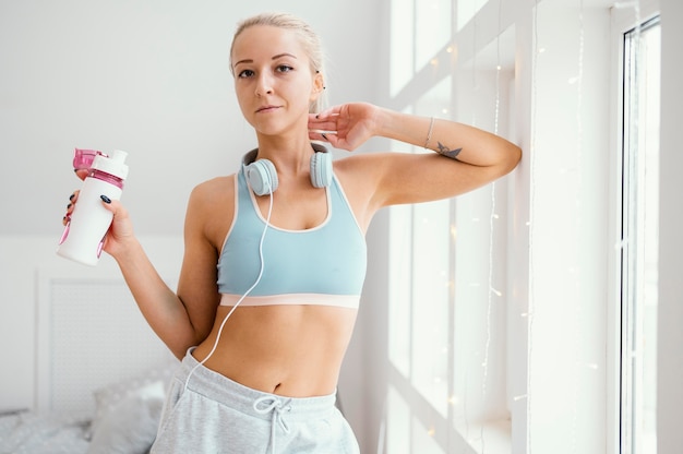 Mulher com fones de ouvido e garrafa de água