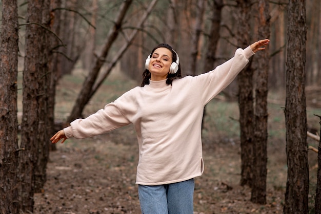 Foto grátis mulher com fones de ouvido, explorando a natureza