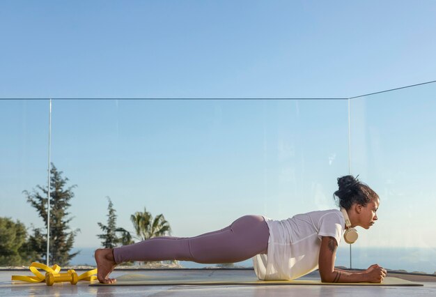 Mulher com fones de ouvido fazendo exercícios em casa