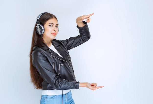 Mulher com fones de ouvido, mostrando o tamanho de algo.