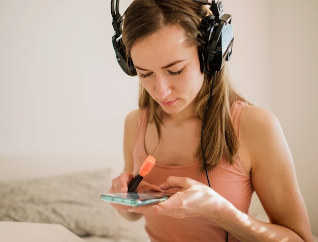 Foto grátis mulher com fones de ouvido segurando smartphone e marcador