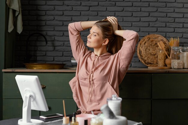 Mulher com foto média amarrando o cabelo dentro de casa