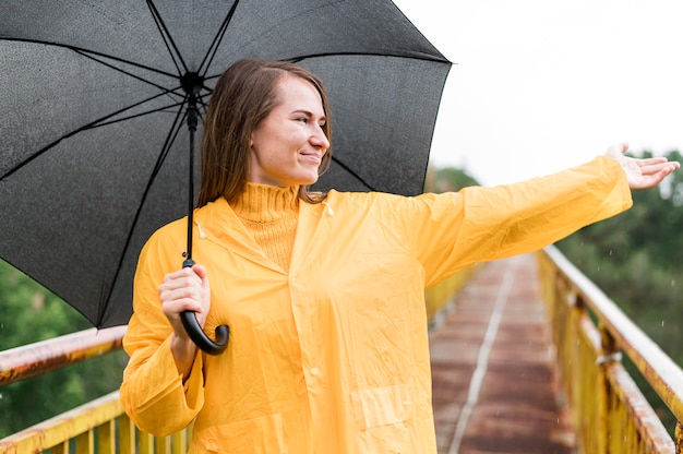 Mulher com guarda-chuva preta, levantando a mão