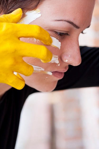 Mulher com linhas de pintura de mão amarela em seu rosto