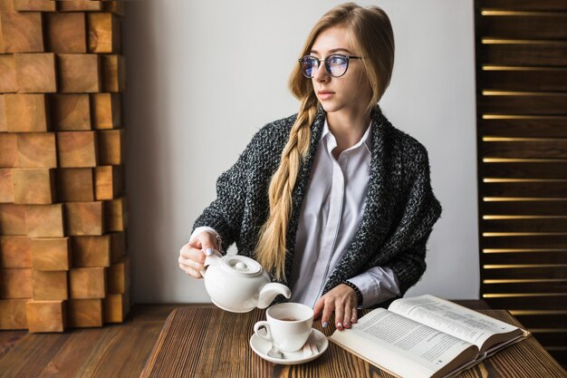 Mulher, com, livro, chá derramando