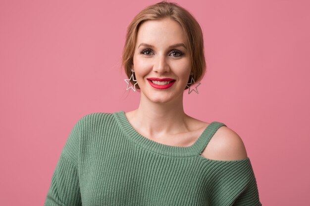 mulher com maquiagem elegante, lábios vermelhos, suéter verde posando em rosa