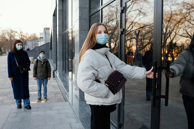 Foto grátis mulher com máscara abrindo porta