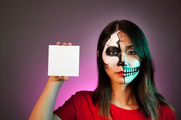 Mulher com máscara de Halloween mostrando cartão