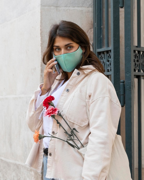 Foto grátis mulher com máscara facial falando ao telefone ao ar livre