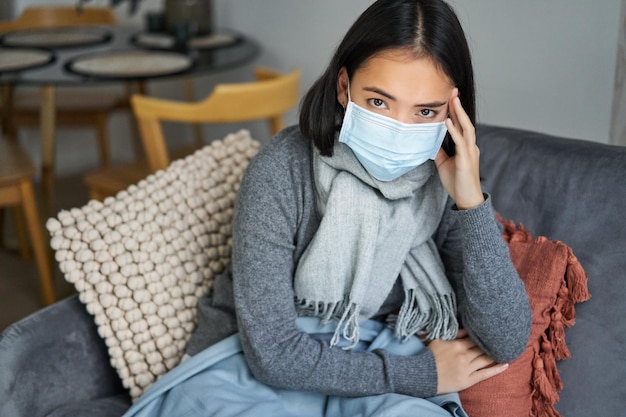 Mulher com máscara facial médica tem covid fica em casa com equipamento de proteção individual pegando gripe sentada