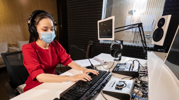 Mulher com máscara facial trabalhando no rádio com equipamento profissional