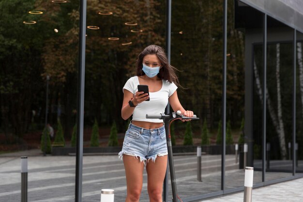 Mulher com máscara médica e scooter ao ar livre