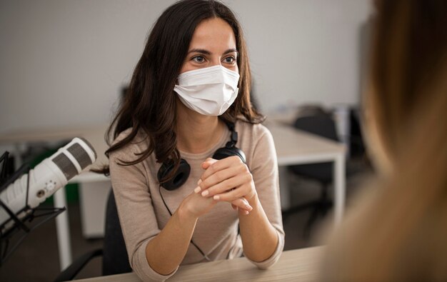 Mulher com máscara médica em um estúdio durante um programa de rádio