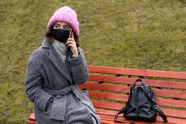 Mulher com máscara médica na cidade conversando ao telefone no banco