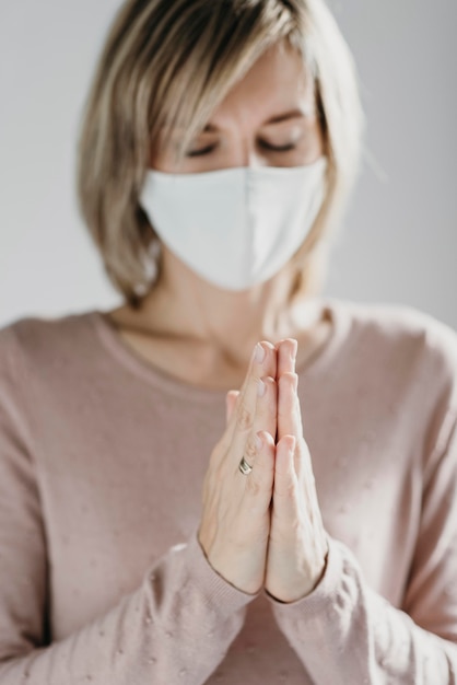 Foto grátis mulher com máscara médica rezando em casa